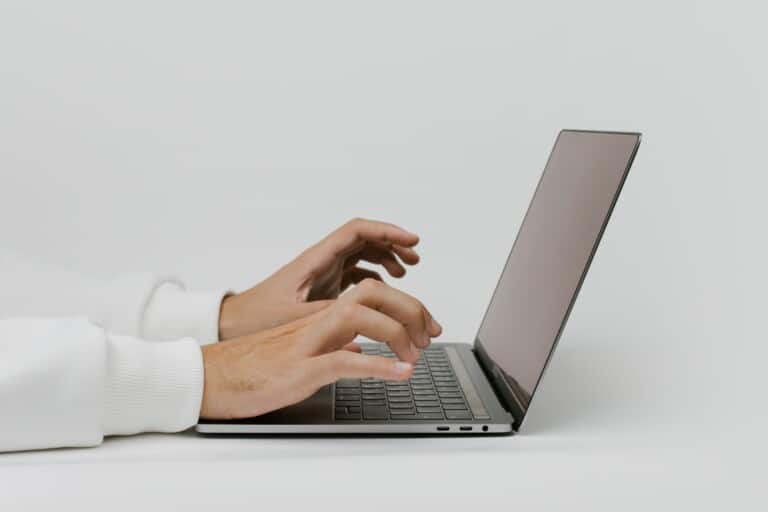 Close-up of hands typing on a laptop keyboard