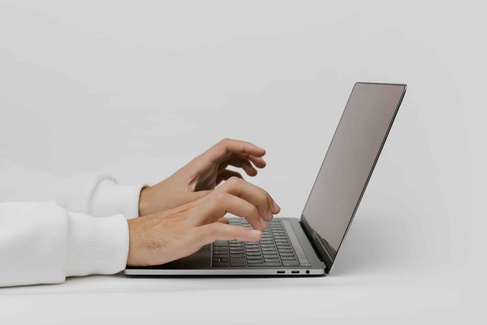 Close-up of hands typing on a laptop keyboard