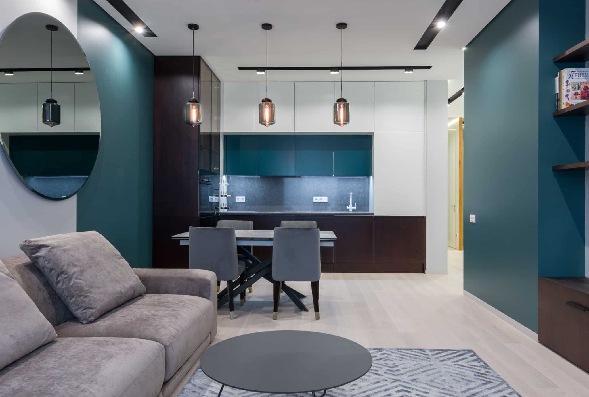 A comfortable furnished living room with sofa, dining table and kitchen visible behind