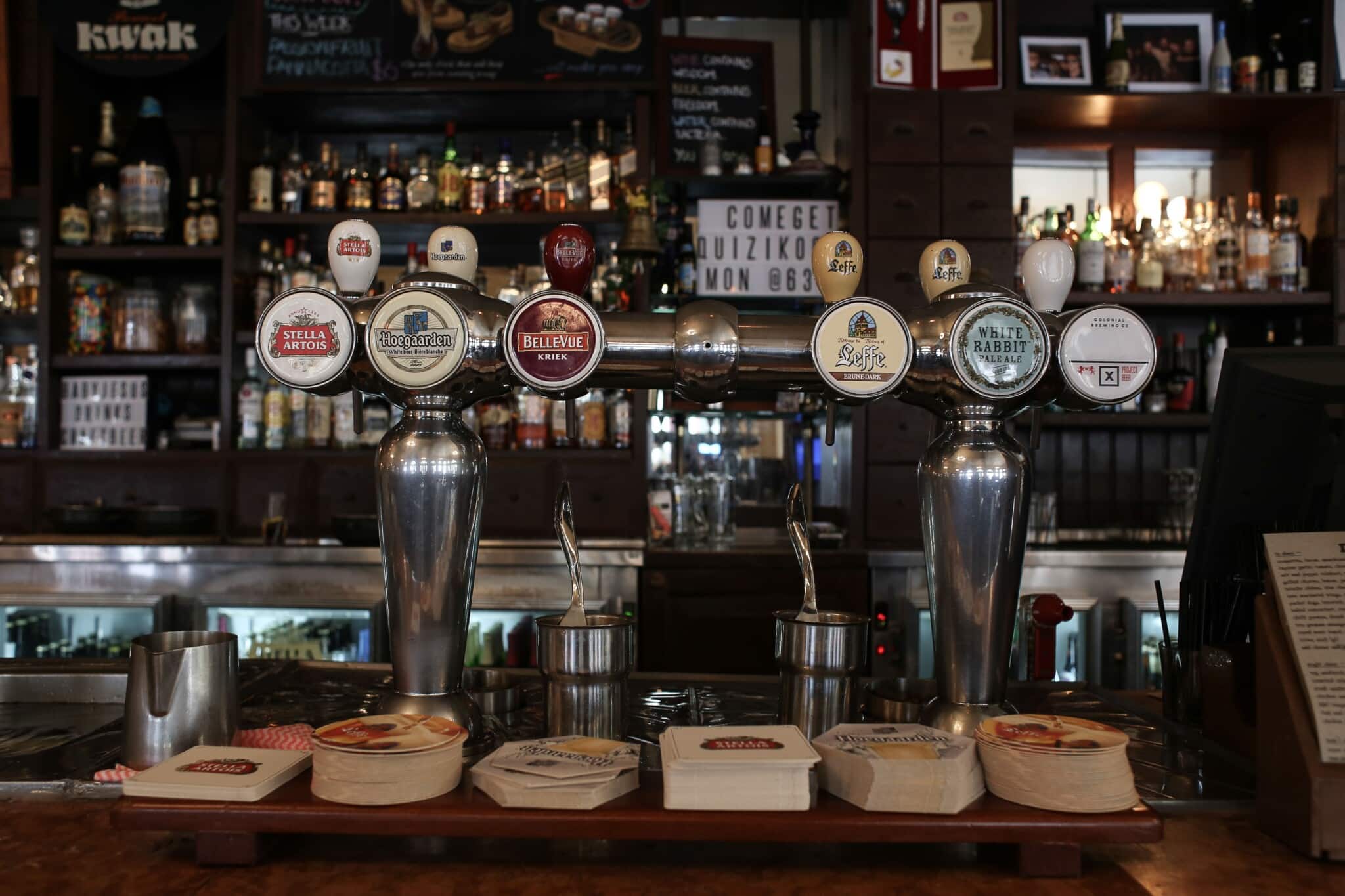 A row of craft beer taps at a cosy pub bar